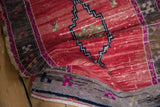 Textural detail of distressed Oushak rug with varied red pile and dark zigzag border.