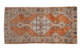 Distressed vintage Oushak runner featuring a terracotta field, ivory diamond medallion, and plant spandrels.
