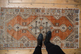 Distressed Oushak runner corner; rust field, beige spandrel, floral border, with even wear and faint foundation.