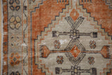 Distressed Oushak rug runner pile showing worn rust, beige, and charcoal geometric motifs.