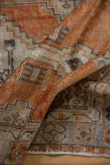 Folded distressed Oushak runner detail, highlighting worn terracotta pile and geometric motifs.