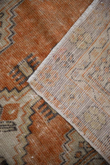 Distressed vintage Oushak rug showing terracotta, ivory, charcoal pile and woven foundation.