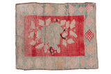 Distressed vintage Oushak rug with light floral bouquet on blush red and checkered green border.