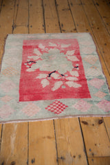 Distressed Oushak rug corner, showing blush, pink, tangerine floral diamond border.
