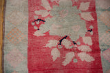 Distressed vintage Oushak rug with blush, cherry red, and pale blue floral motifs.