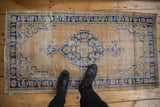 Distressed gold field with navy blue scalloped medallion on vintage Oushak rug.