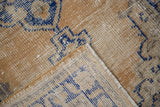 Vintage Distressed Oushak rug corner, showing textured pile, navy blue motif, and exposed foundation.