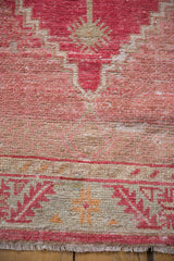 Serrated leaf border of a distressed Oushak rug, with varied pile texture in cherry red and ivory.