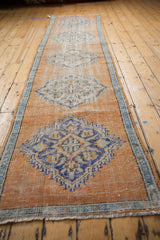 Distressed vintage Oushak runner end, worn tangerine orange pile, banded border, sky blue medallion.