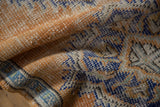 Distressed Oushak rug pile with visible knot heads, foundation, pale orange, and sky blue.