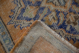 Distressed orange and blue Oushak rug pile, woven foundation, and orange selvage on turned corner.
