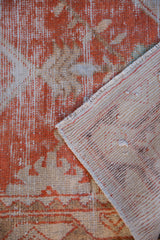 Distressed vintage Oushak rug showing worn pile, visible hand-knotted foundation, pale brick red and ivory.