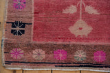 Vintage distressed Oushak rug corner, showing bright fuchsia floral motifs and textured pile.