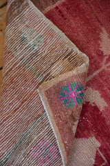 Distressed Oushak rug pile with fuchsia, green, pink geometric motif and hand-knotted back.