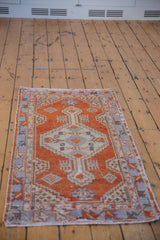 Corner detail of distressed Oushak rug; geometric floral patterns in red, ivory, pale blue.