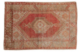 Distressed vintage Oushak rug with faded red serrated medallion and abrashed beige field.
