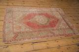 Decorative, worn texture of a vintage Oushak rug, showing mostly even wear and raspberry red tones.