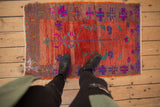 Textured distressed Oushak rug showcasing playful floral motifs and abrashed madder red ground.