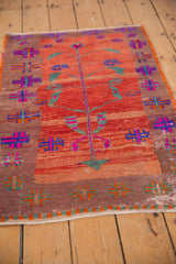 Distressed Oushak rug shows a colorful geometric border, abrashed red field, magenta tree motif.