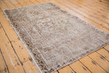 Worn beige, ivory, and copper brown floral patterns on a distressed Oushak rug detail.