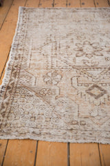 Secured end of distressed Oushak rug, with visible worn foundation and short fringe.
