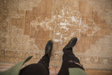 Distressed vintage Oushak rug featuring bronze, coffee, and ivory geometric vinery with exposed foundation.