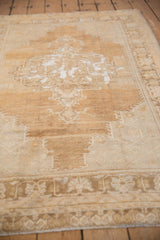 Distressed vintage Oushak rug's abrashed field with geometric plants in beige and bronze.