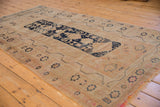 Vintage Oushak rug corner: navy starbursts, simplistic pomegranate border, visible wear, and fringe.