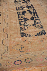 Vintage Oushak rug with navy blue starburst motifs on beige, showing wear to knot heads.