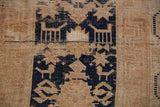 Vintage Oushak rug with navy stylized motifs and worn beige pile showing foundation.