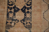 Vintage Oushak rug's navy geometric pattern on beige, with foundation showing through.