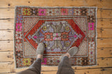 Distressed Oushak rug corner, showing worn pile, fringe, and fuchsia-rust motifs.