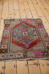 Distressed vintage Oushak rug corner revealing low pile, fuchsia florals, rust border.