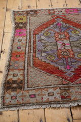 Distressed vintage Oushak rug corner showing colorful oversized floral border designs and fringe.