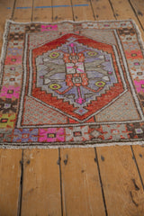 Worn pile texture on a distressed Oushak rug's fringed edge with colorful floral border.