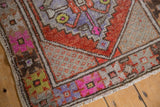 Distressed Oushak rug corner with worn pile, rust, fuchsia, and purple floral border.