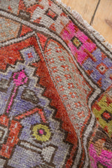 Distressed vintage Oushak rug pile with vivid rust, fuchsia, purple pops, and worn texture.