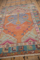 Distressed Oushak rug border featuring tangerine, teal, pink geometric patterns and fringe.