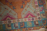 Corner of distressed Oushak rug showing pink serrated leaves and geometric blue and green borders.