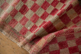 Distressed Oushak rug pile with cherry red and beige checkered pattern.
