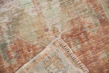 Folded corner of vintage distressed Oushak rug, showing worn pile, visible foundation, and fringe.