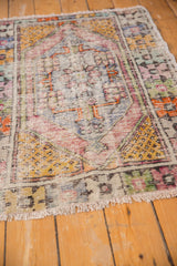Vintage Distressed Oushak rug's worn pile texture, highlighting saffron yellow seed motifs and softened plum, blush colors.