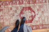 Distressed vintage Oushak runner with cherry red and ivory geometric-floral patterns and worn texture.