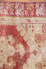 Vintage distressed Oushak rug's cherry red and ivory geometric pattern with visible wear.