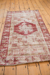 End of distressed Oushak runner, showing worn cherry red, antique ivory pile and fringe.