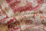 Distressed Oushak rug texture revealing cherry red, ivory, and visible foundation wear.
