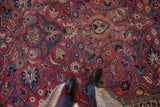 Vintage Meshed carpet's cochineal red field, sprawling blue tendrils and palmettes.