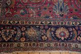Vintage Meshed carpet detail showing worn fringe, intricate navy border, and cochineal floral motifs.