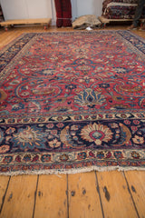 Vintage Persian Meshed carpet end displays cochineal red field, navy border, scrolling tendrils, and ivory fringe.