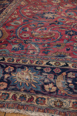 Sprawling tendrils and palmettoes in cochineal red and navy blue on vintage Meshed rug.
